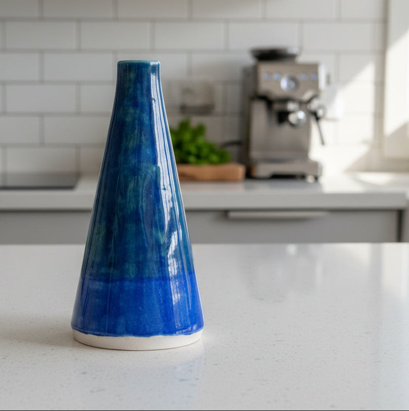 Blue ceramic oil bottle on a kitchen counter with a blurred background