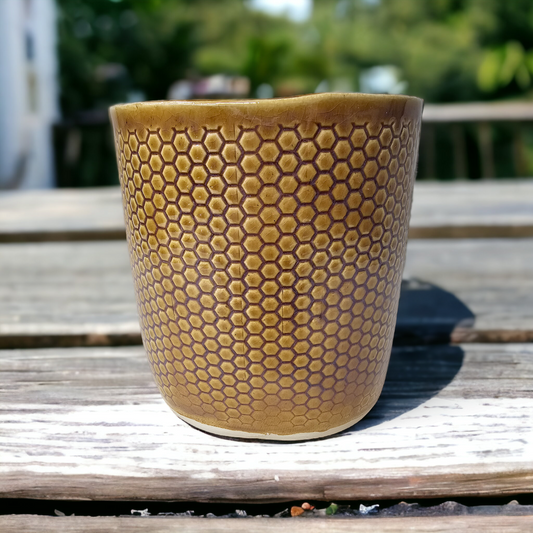 Utensil holder embossed with a honeycomb design and glazed in amber.